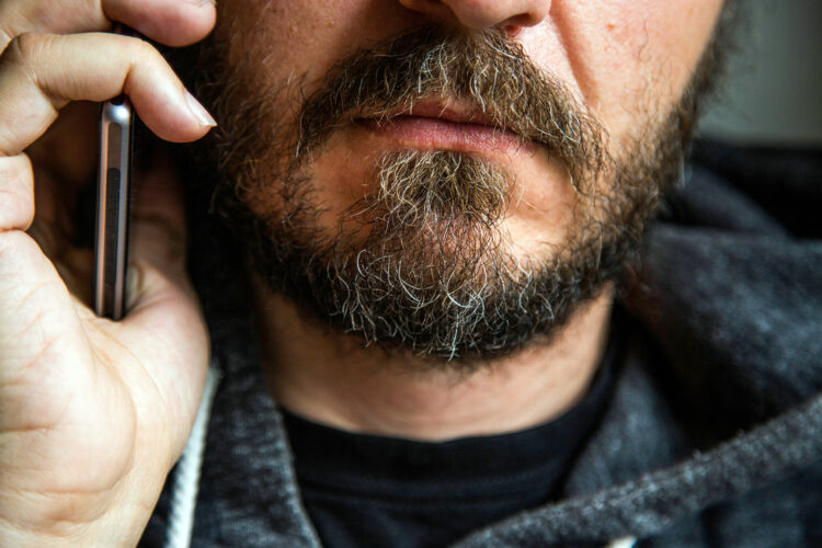 un hombre con barba habla a través de su teléfono móvil